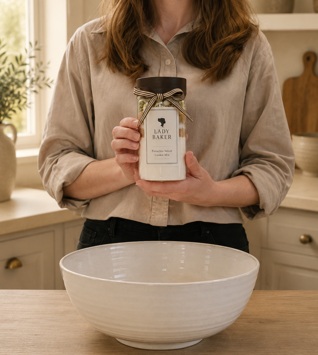 Person holding a jar labeled 'Lady Baker' in a kitchen setting with a large white bowl on the counter.