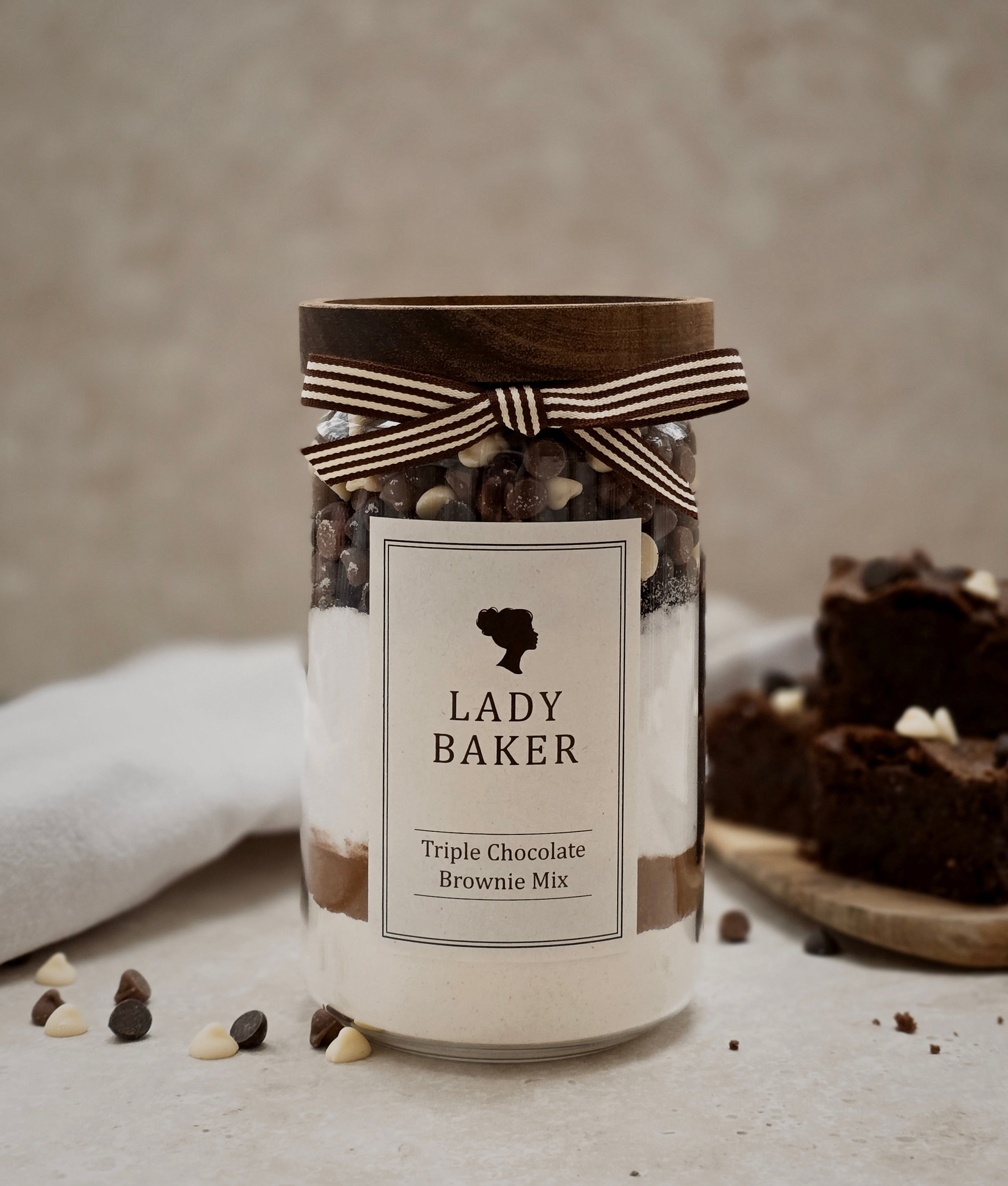 Lady Baker glass Jar of Lady Baker triple chocolate brownie mix with a bow on a neutral background