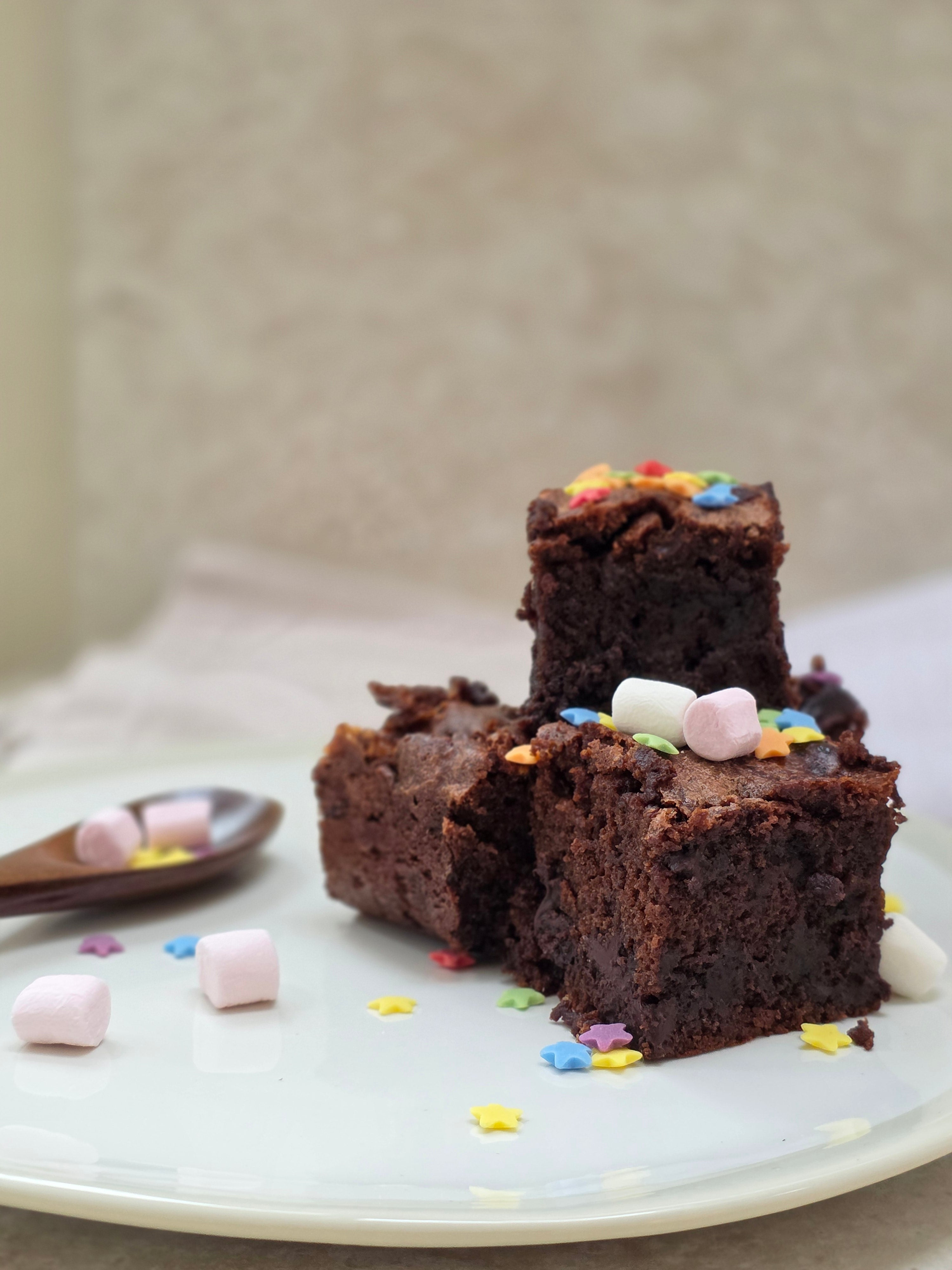 Lady Baker Magic Brownie Mix - rich chocolate brownie topped with colourful sprinkles and mini marshmallows on a white plate.